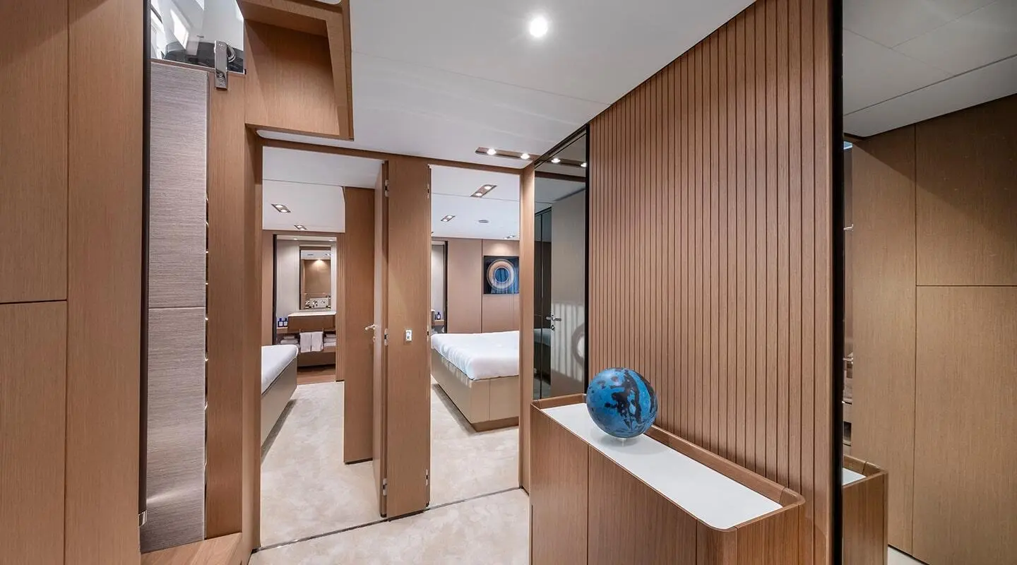 Spica yacht master cabin with wood cabinetry, bed, and blue decorative vase