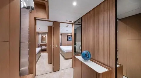 Spica yacht master cabin with wood cabinetry, bed, and blue decorative vase