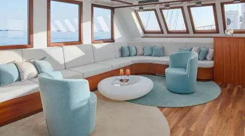Corsario luxury gulet sailing interior with white cushions and blue seating at sunset