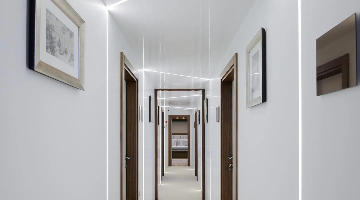 Long white hallway on yacht with framed photos and doors along sides