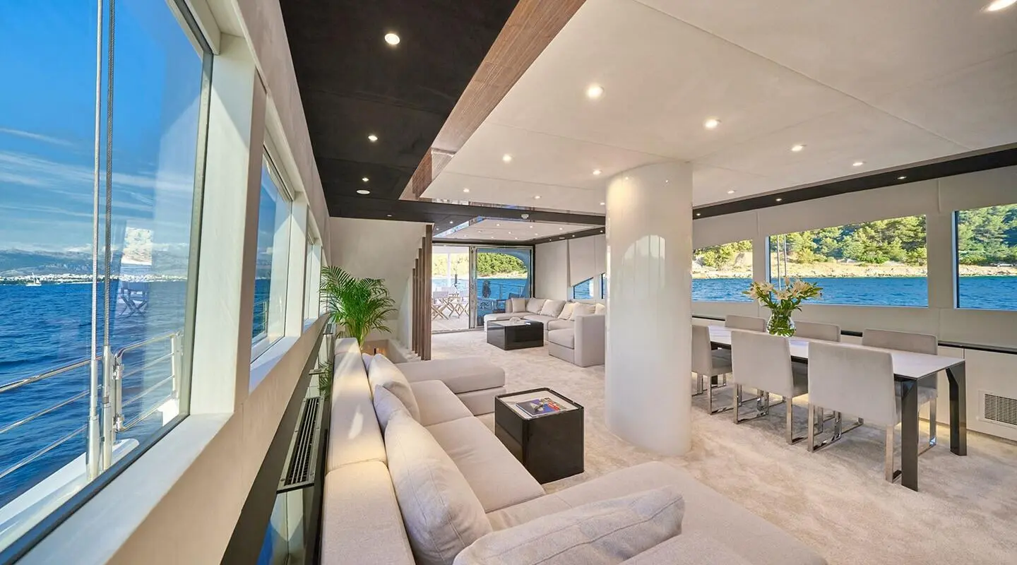 Interior of Acapella yacht salon with white seating and large windows