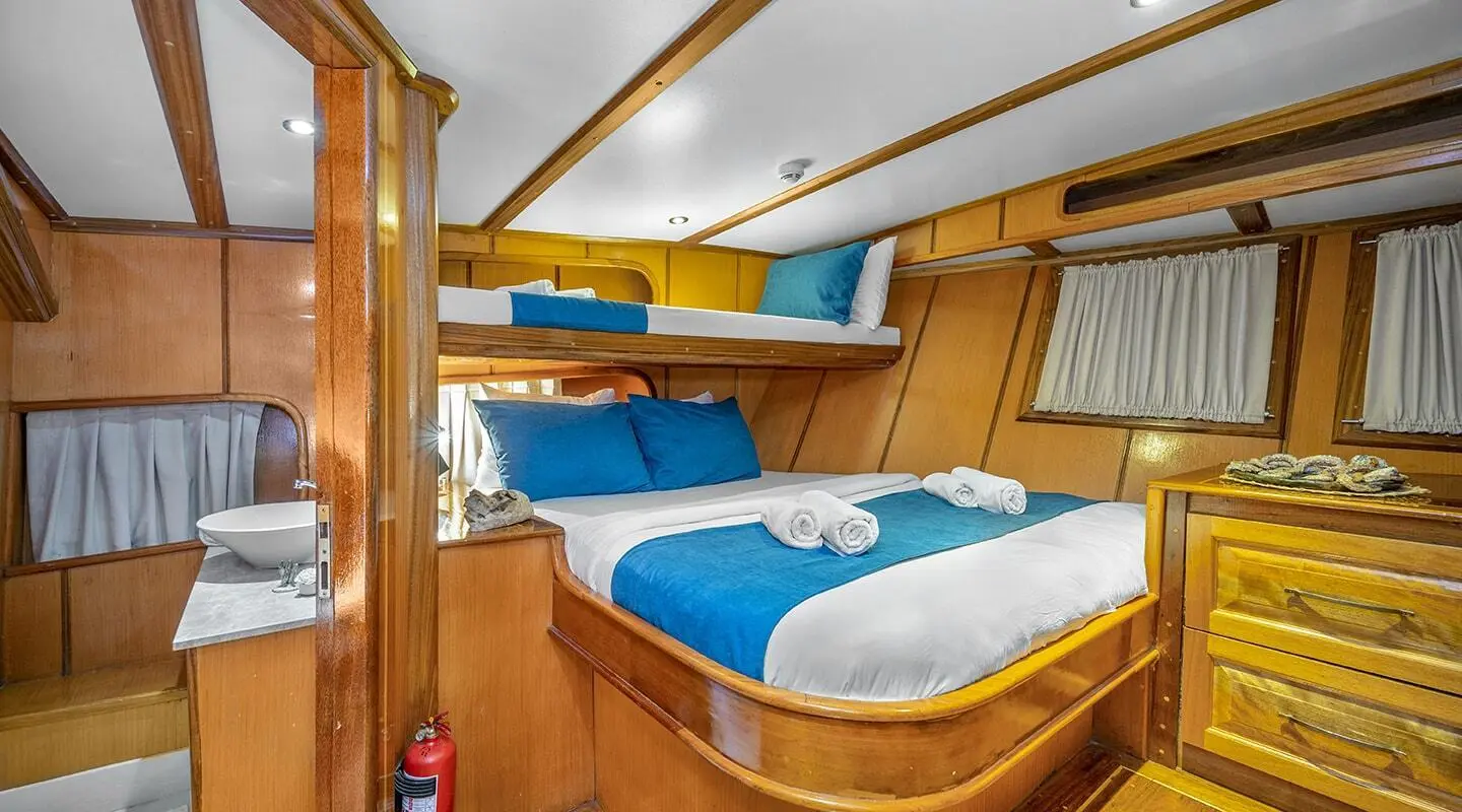 Interior of a luxury gulet with blue and white bedding and wood trim
