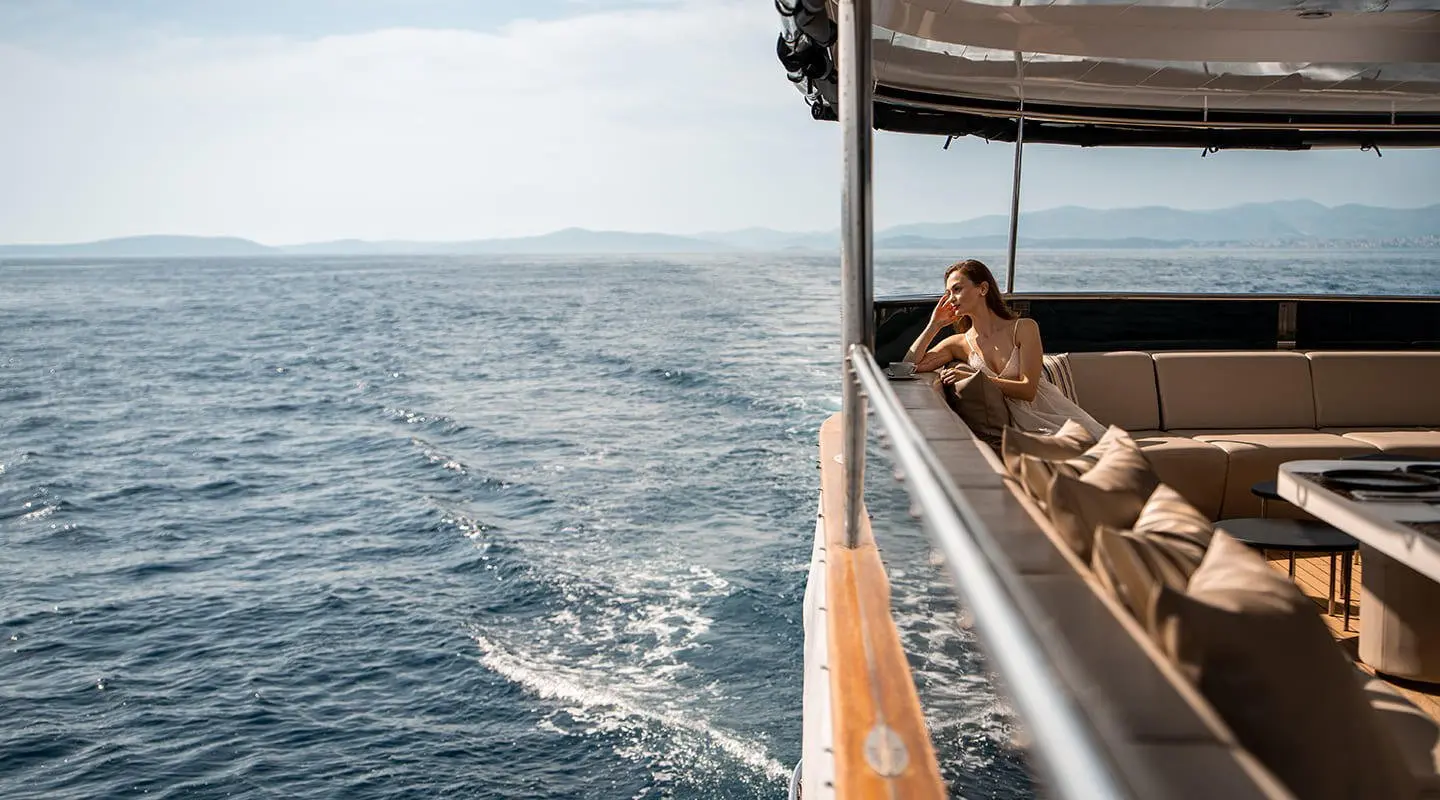 Cristal yacht deck with railing, calm sea, distant horizon at sunset