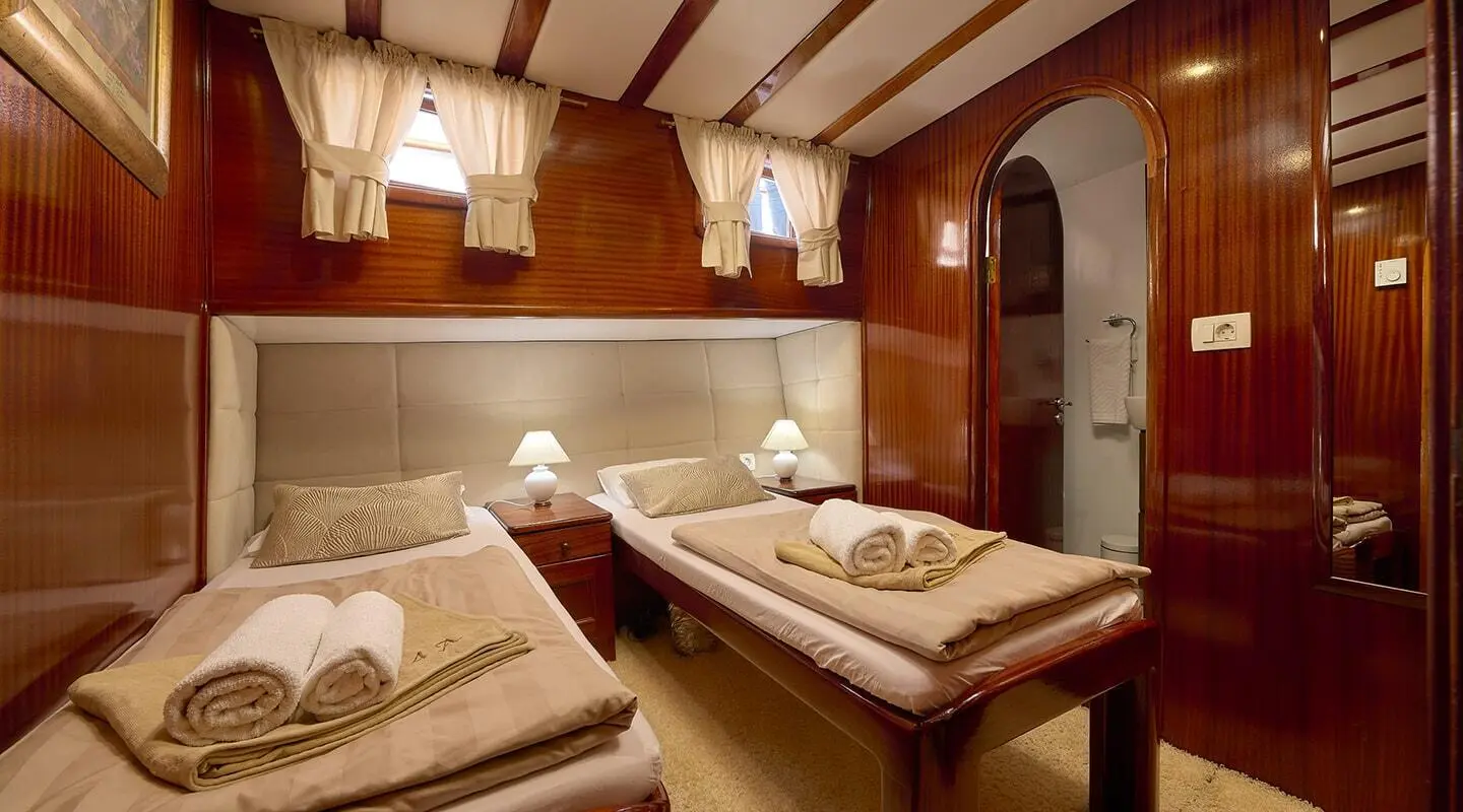 Interior of a luxury yacht salon with wooden beams, sofa seating, and a central table