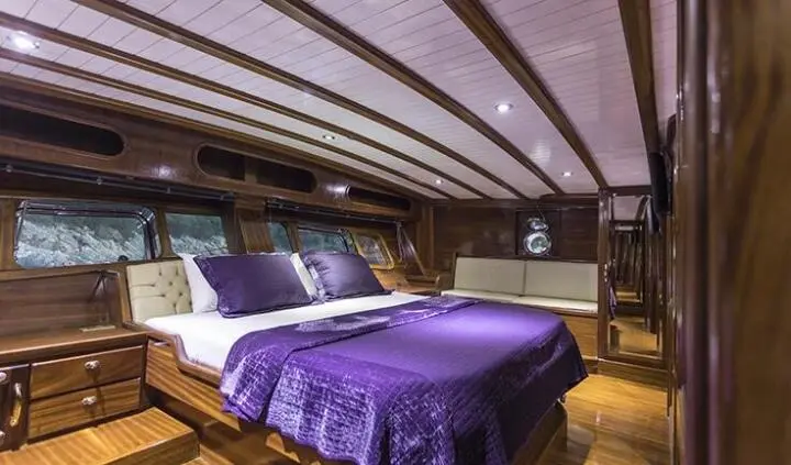 Master cabin with king bed and purple bedding on Grace 1 yacht interior