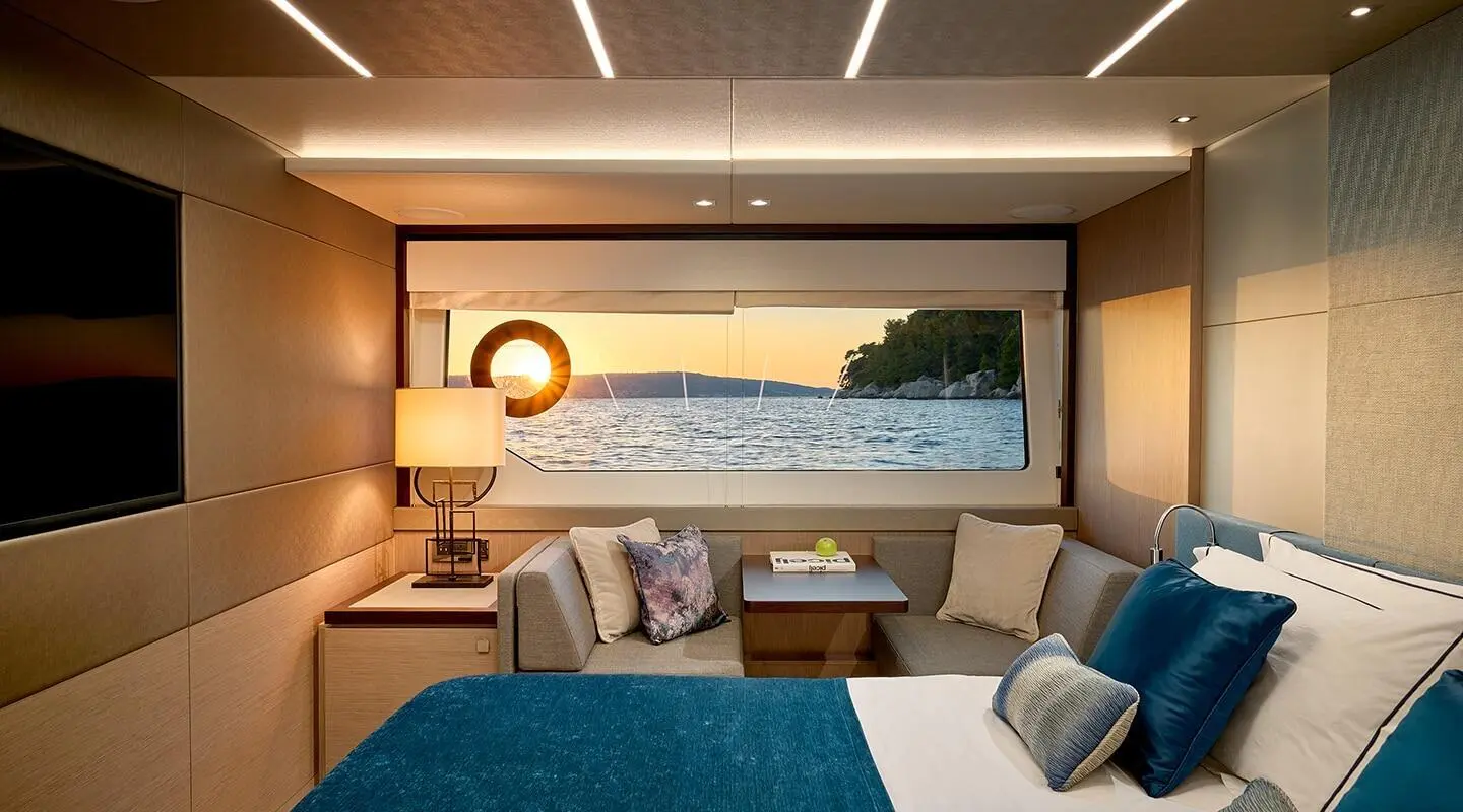 Interior of a luxury yacht bedroom with a large window view and bed linens