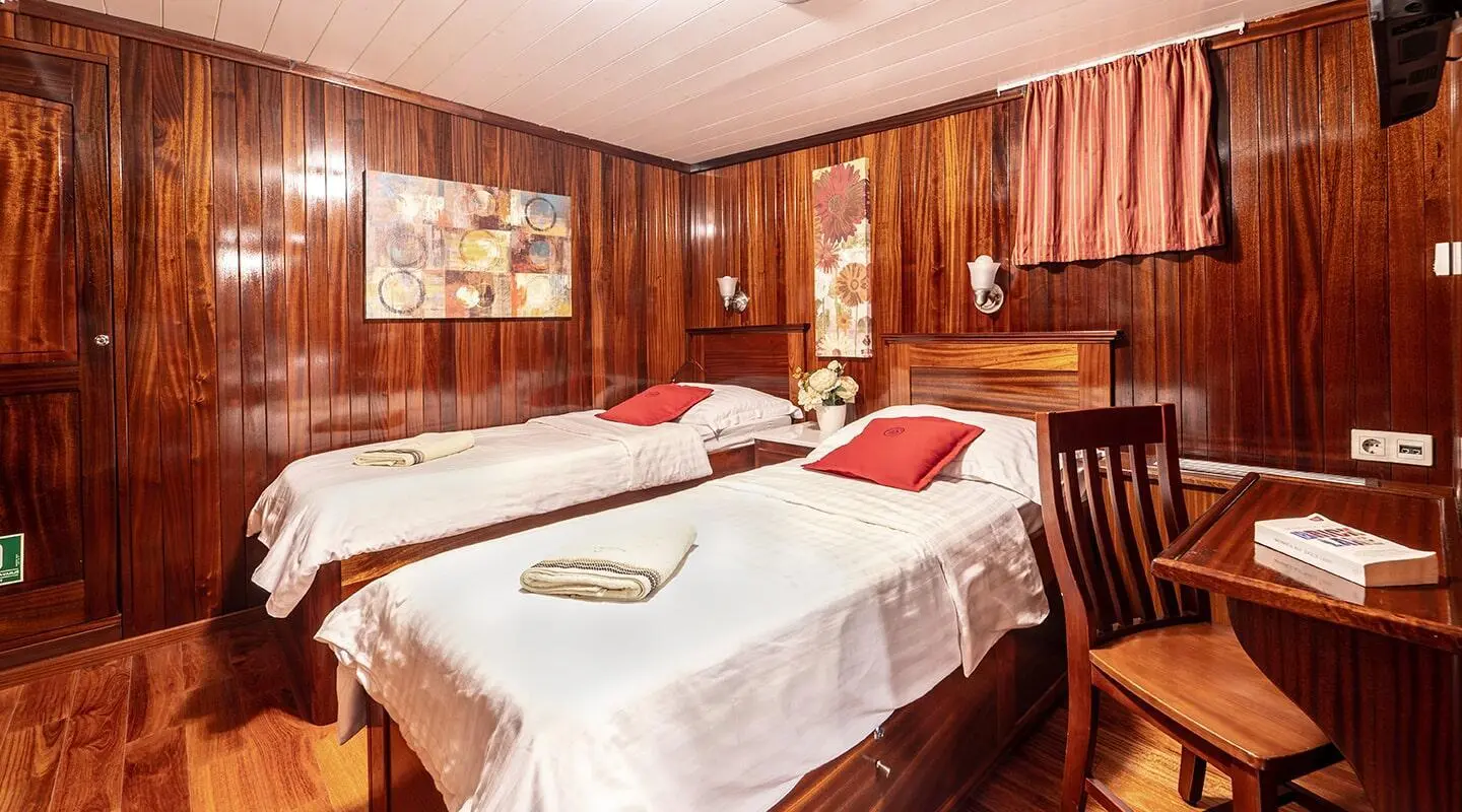 Cesarica luxury gulet interior with twin beds, warm wood walls, and white bedding