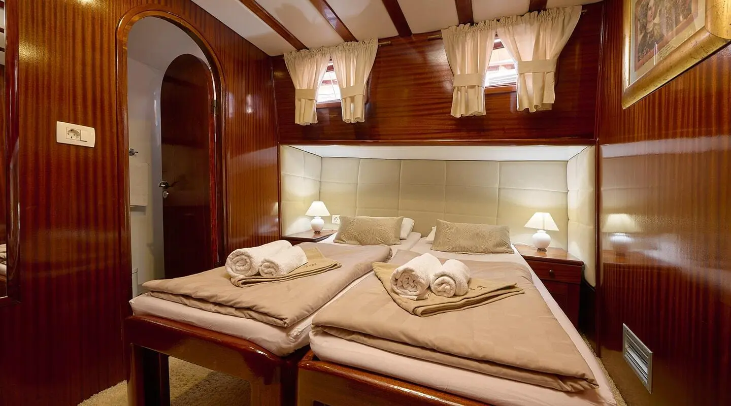 Interior of Linda gulet with twin cabin beds, warm lighting, and neatly made linens