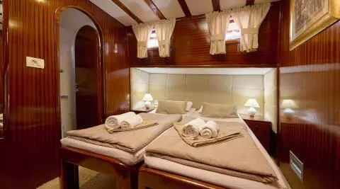 Interior of Linda gulet with twin cabin beds, warm lighting, and neatly made linens