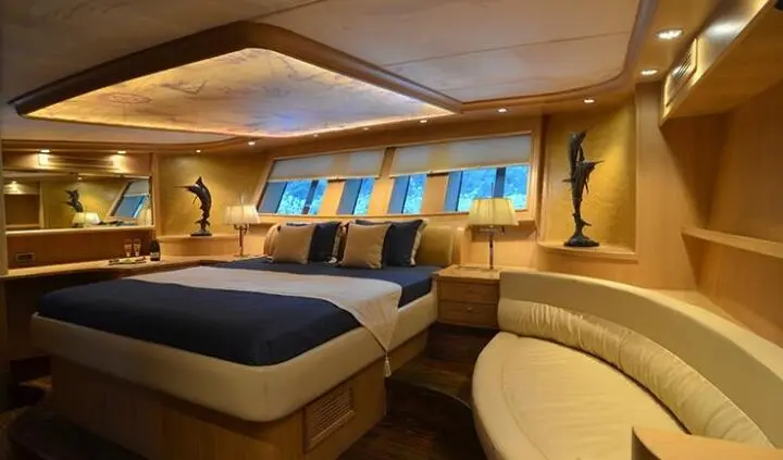 Two large beds in a cabin with blue accent pillows and porthole windows