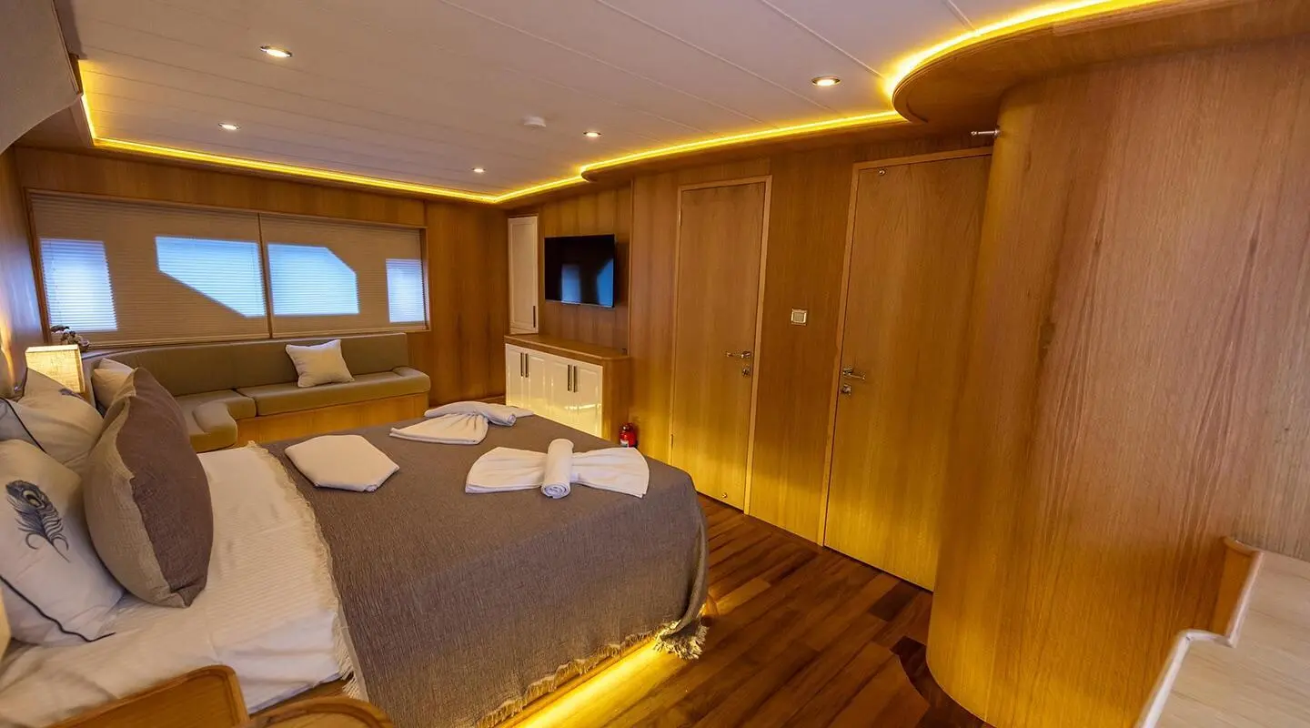 Interior of Simay M yacht with warm wooden panels and lit ceiling, beds and seating