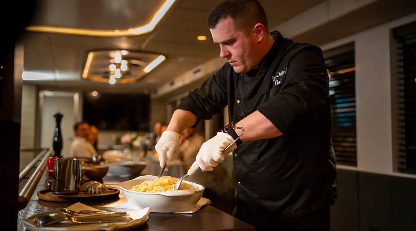 Chef plating dish aboard Anima Maris yacht in a busy galley kitchen