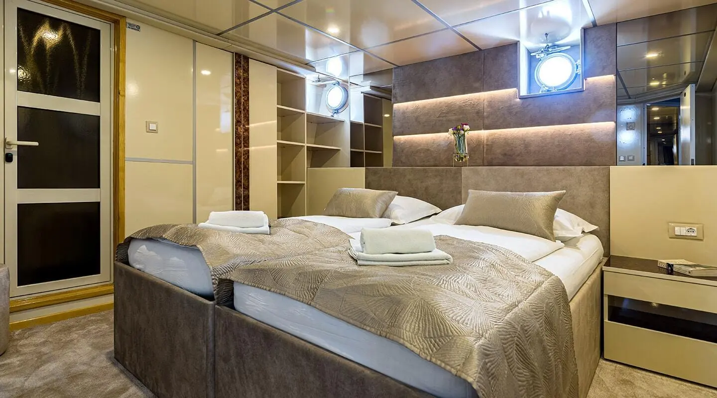 Luxurious yacht Melody stateroom with plush bedding and warm lighting