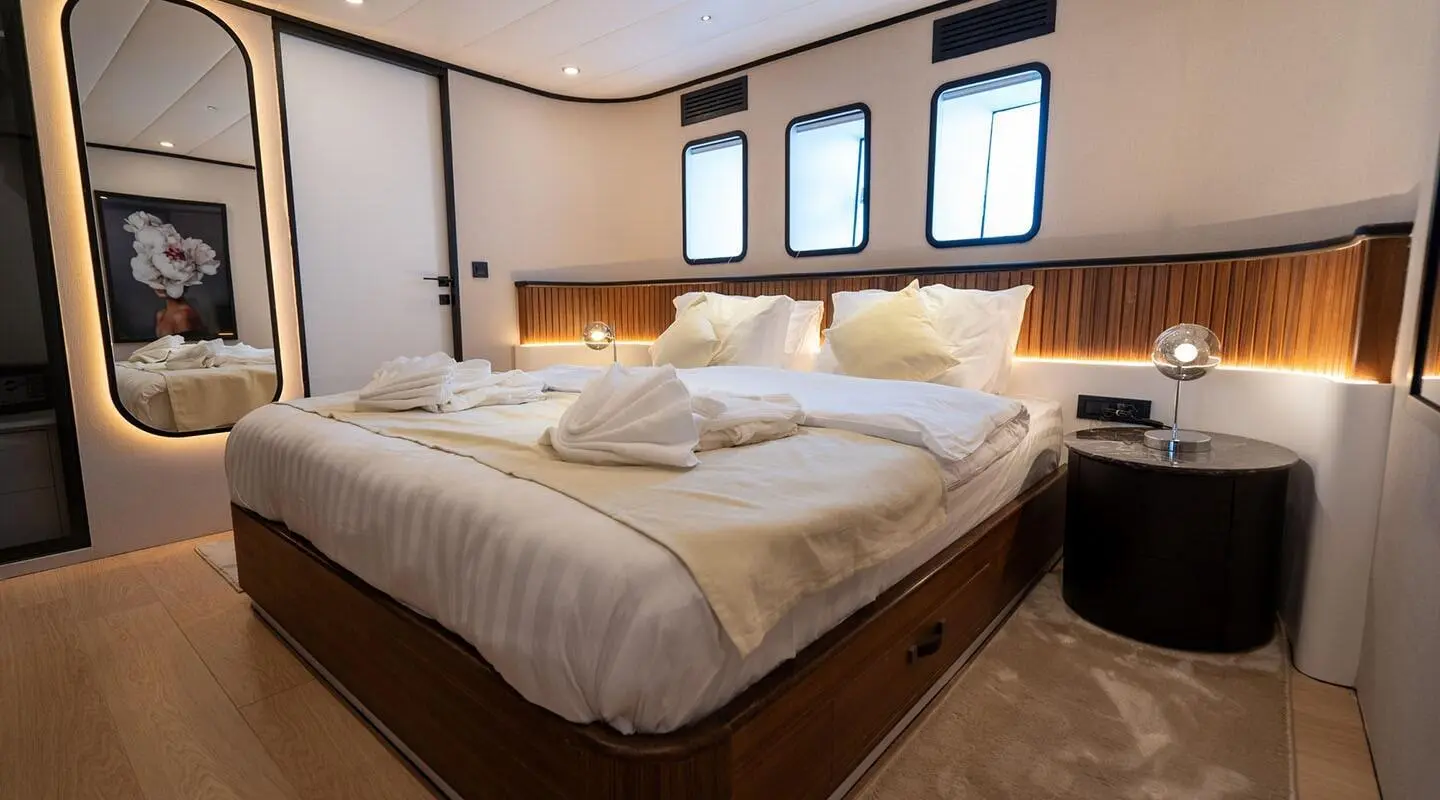 A bedroom with a large bed, wooden headboard panel, and bedside lamps