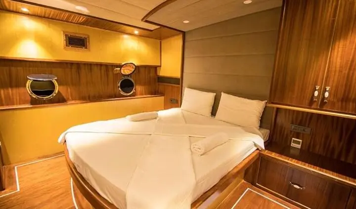 Nevra Queen gulet cabin interior with two single beds and warm wood accents