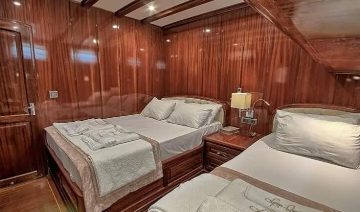 Lycian Queen yacht interior cabin with three single beds and wooden paneling