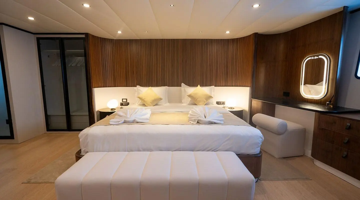 Luxurious bedroom on De Love yacht with white bed and wood panels