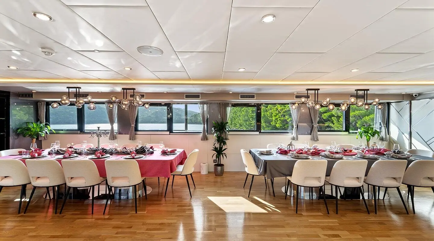 Elegant yacht Freedom dining area with long table set for guests and large windows
