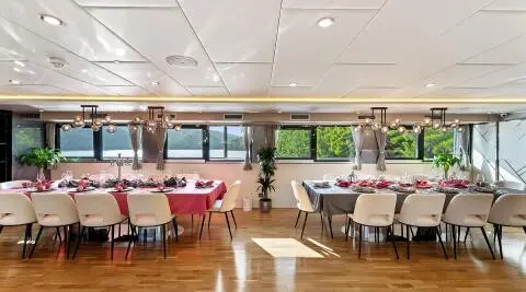 Elegant yacht Freedom dining area with long table set for guests and large windows