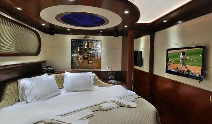 Dolce Mare cabin interior with plush bed, ambient ceiling lighting, and wall-mounted TV