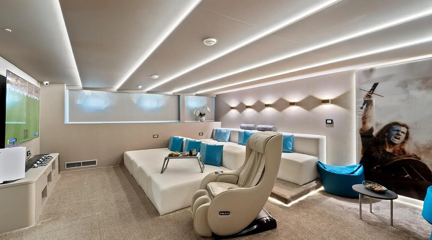 Luxurious yacht cinema room with row of white recliners and blue-accented seating