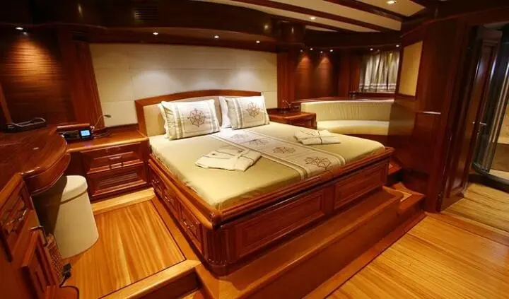 Master cabin with king bed, wood tones, ensuite bathroom visible, Kaya Guneri 5