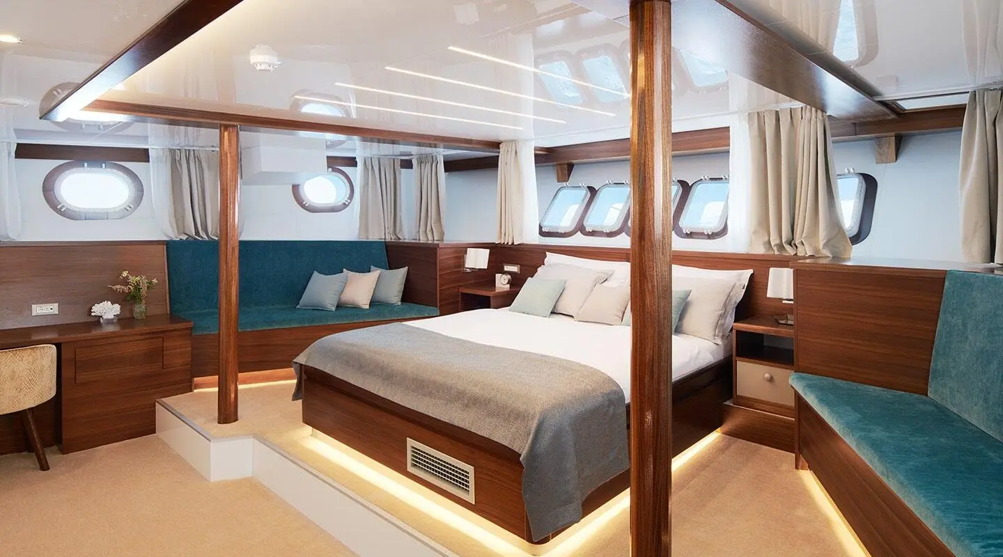 Corsario yacht interior with two beds, wooden cabinetry, and large windows.