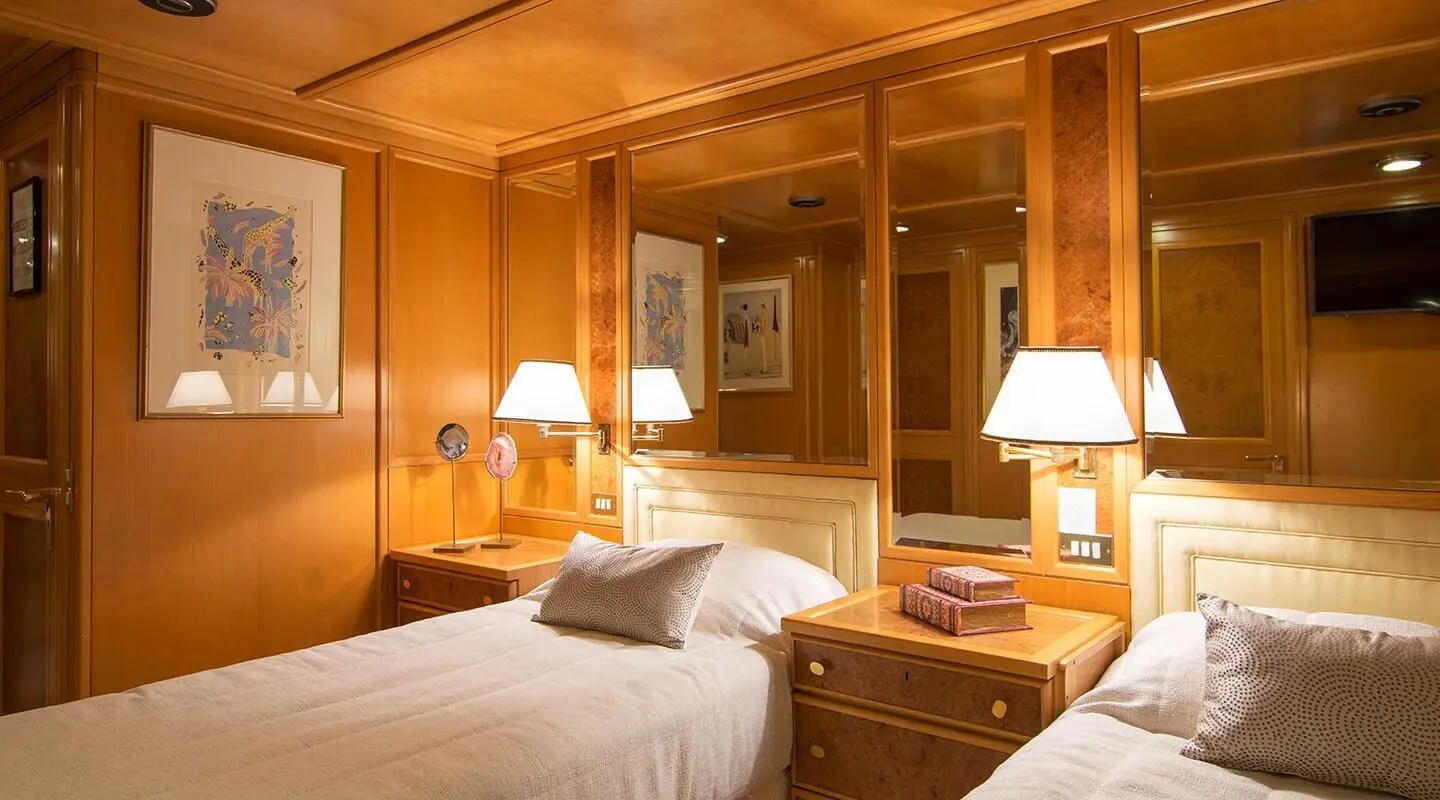 O'Natalina yacht interior with twin cabin, wood paneling, two beds, lamps, and framed art