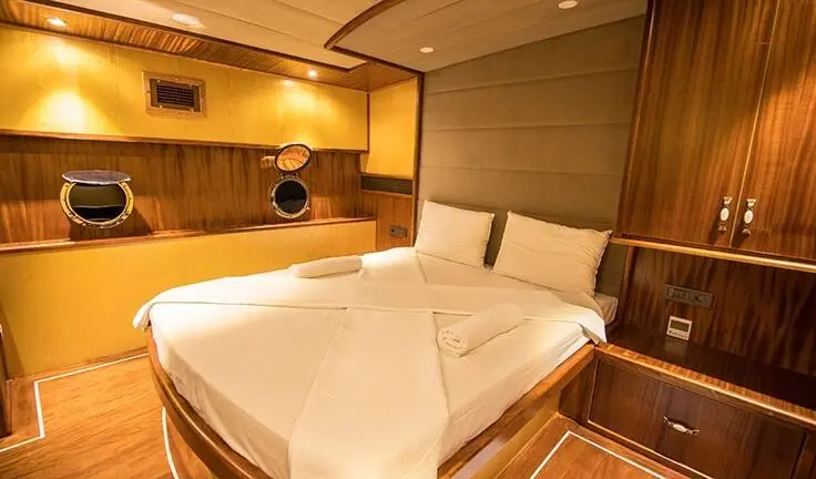 Nevra Queen gulet cabin interior with two single beds and wooden hues