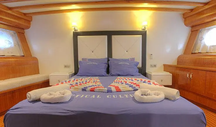 Angelo II master cabin with king bed, navy blue upholstery, and ensuite view