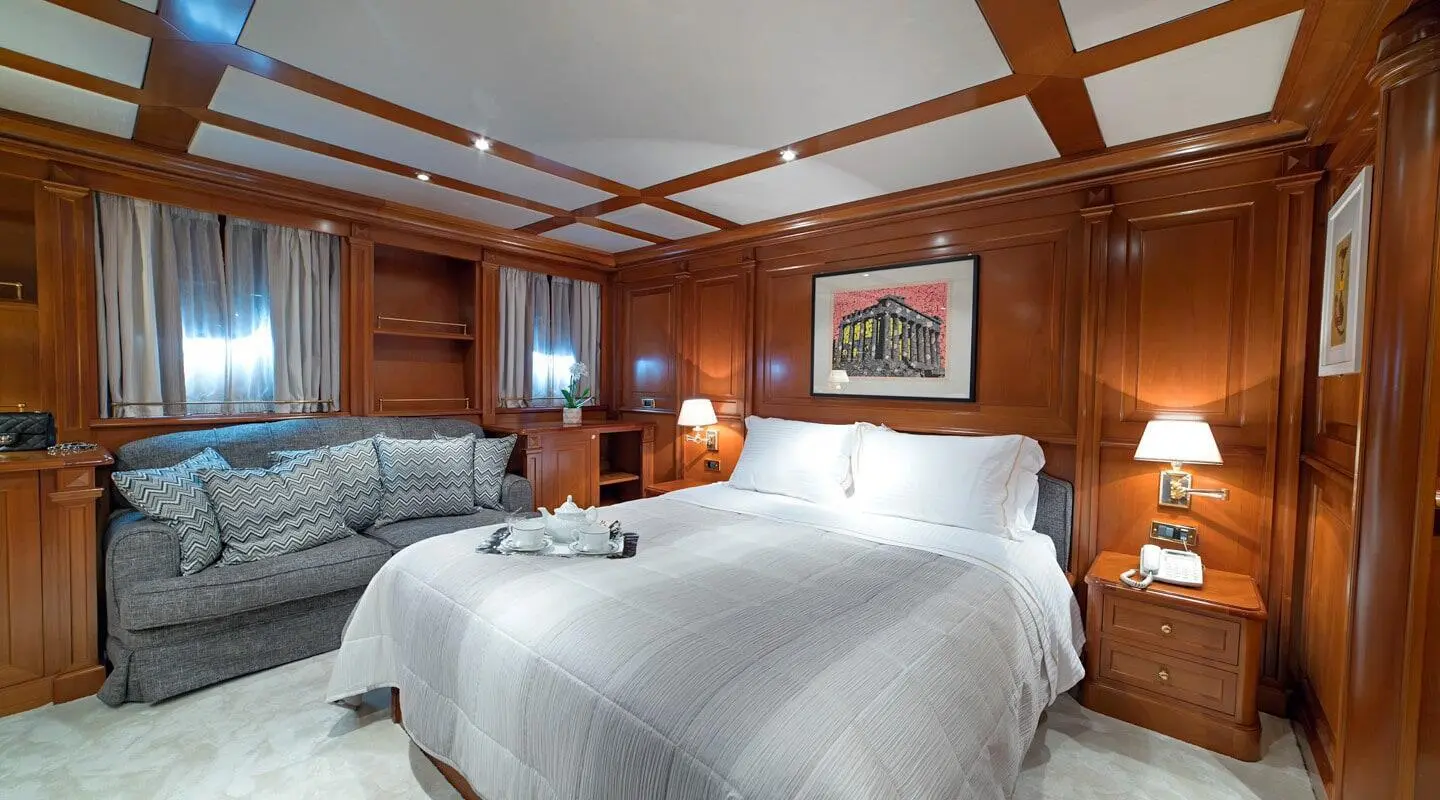 Aquila yacht bedroom with two beds, wood-paneled walls, and bedside lamps