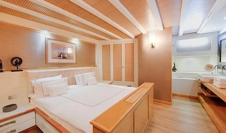 Cobra King yacht master cabin with king bed, wooden beams, and ensuite doorway