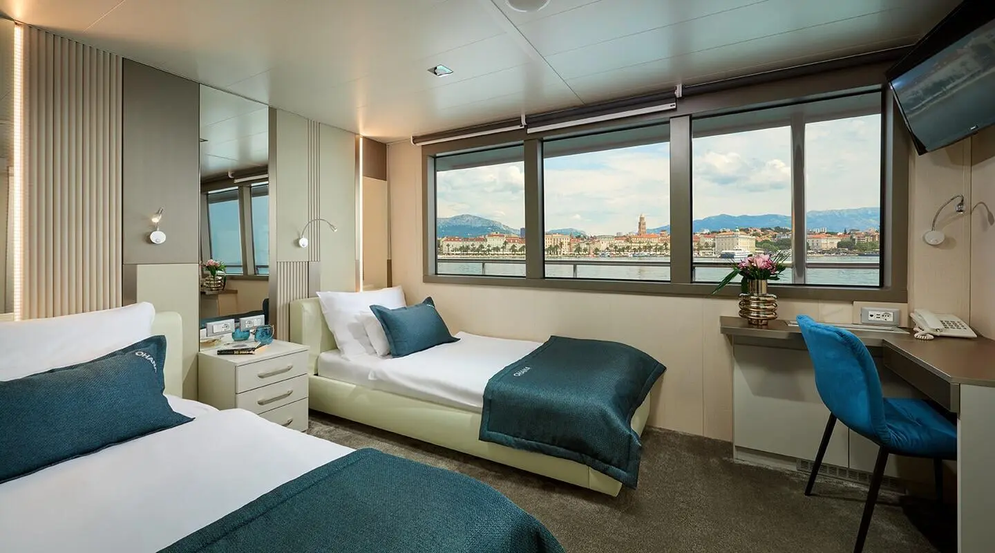 Interior of Ohana luxury yacht deck: bed, windows, seating with blue throw
