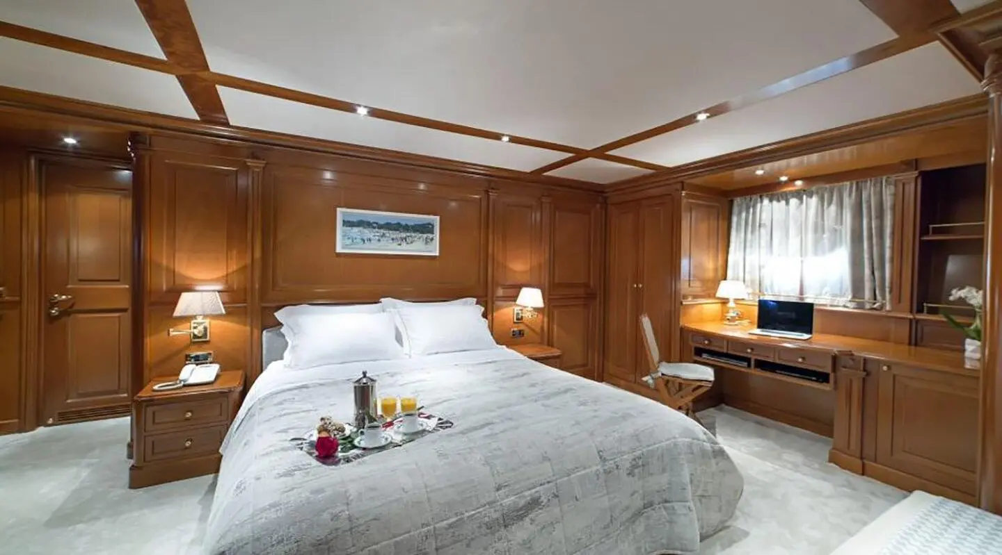 Aqua yacht Aquila master cabin on lower deck with bed, wood paneling, and seating area.