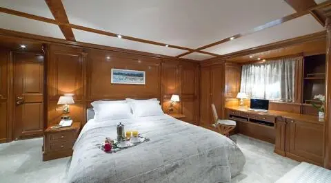 Aqua yacht Aquila master cabin on lower deck with bed, wood paneling, and seating area.