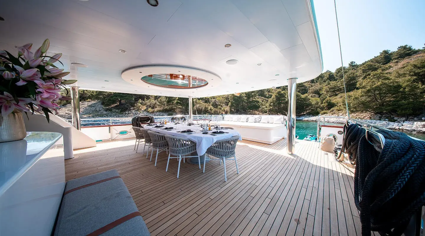 Nocturno yacht dining deck at sunset with table setup and chairs