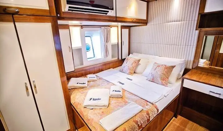 Cozy master cabin on Maske 2 yacht with bed, pillows, and reading light