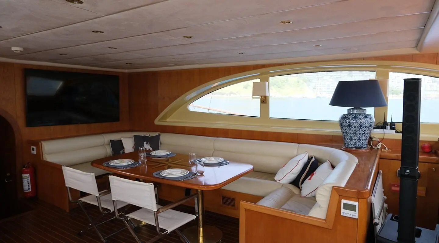 Cozy yacht interior with wooden cabinetry, seating, and table setup near a window