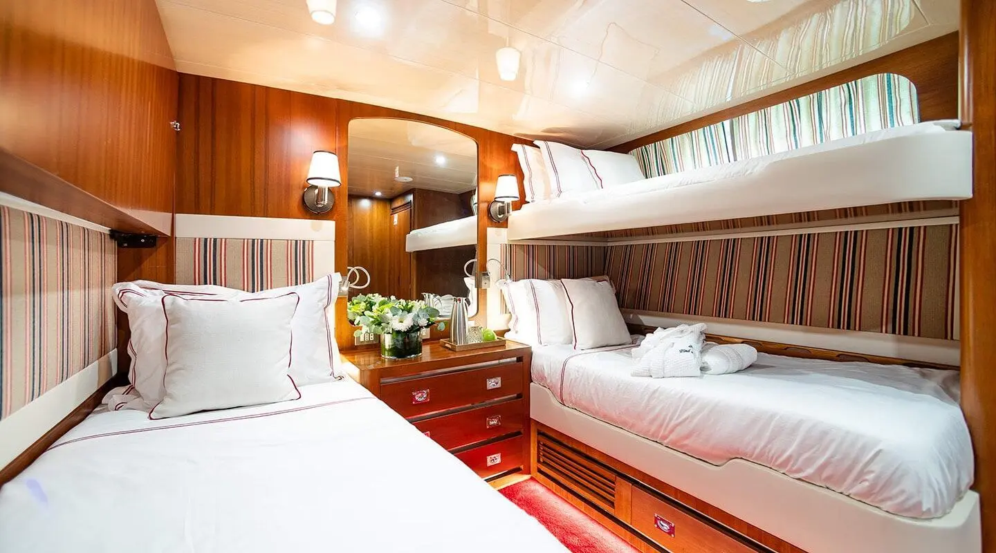 Interior of Wind Of Fortune yacht with twin beds, wood paneling, and warm lighting