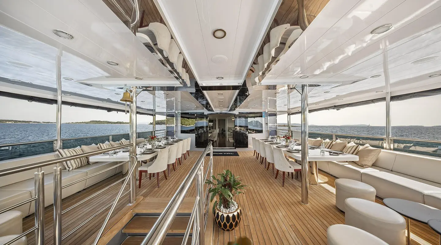 Elegant outdoor dining on Cristal yacht deck with wooden floor and white chairs