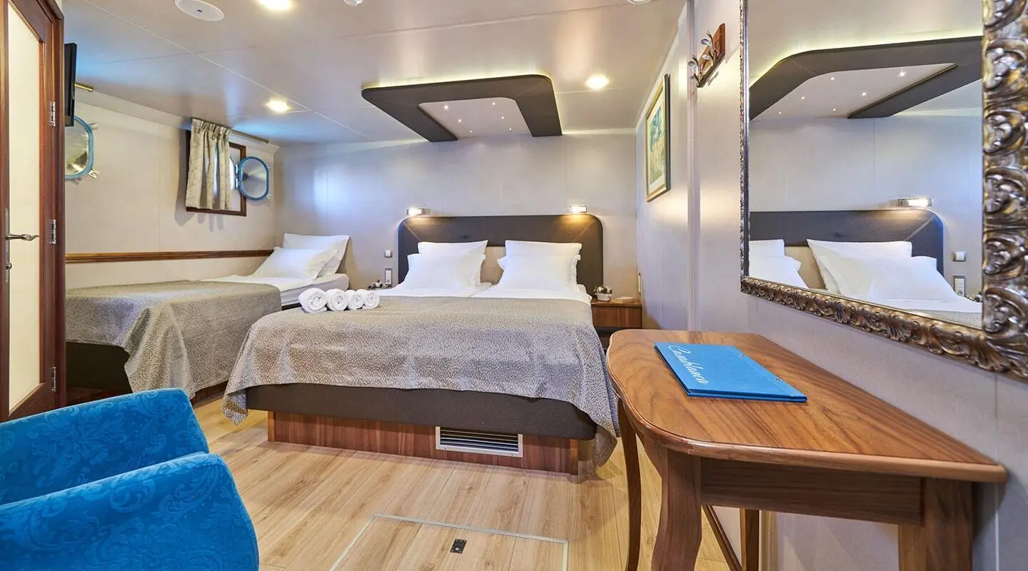Casablanca motor yacht interior with twin beds, wooden floors, and seating area
