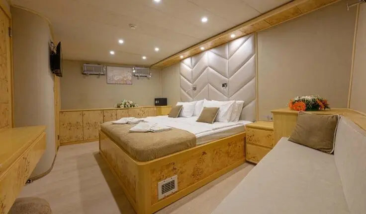 Cozy master cabin on Belgin Sultan yacht with padded headboard and beige decor