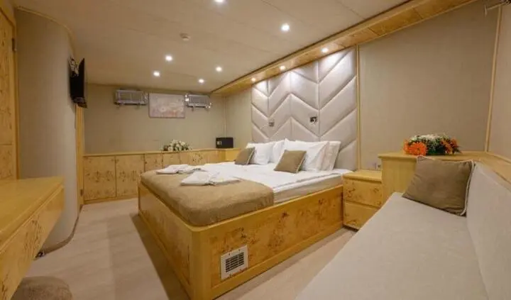 Cozy master cabin on Belgin Sultan yacht with padded headboard and beige decor