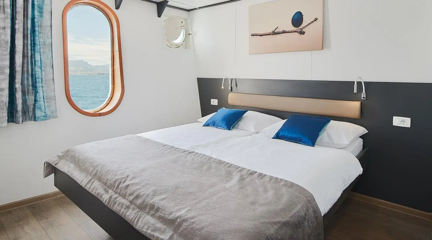 Interior of Lupus Mare yacht guest cabin with two single beds and blue pillows