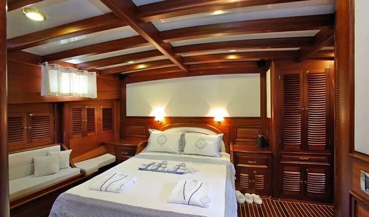 Cozy cabin interior with a bed, wooden walls, and warm lighting aboard Kaya Guneri 4