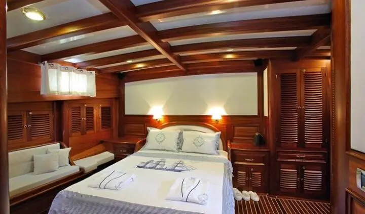 Cozy cabin interior with a bed, wooden walls, and warm lighting aboard Kaya Guneri 4