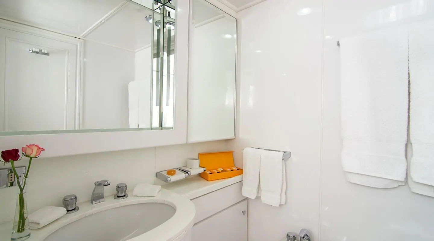 Interior view of a luxurious yacht bathroom with white fittings and orange towel
