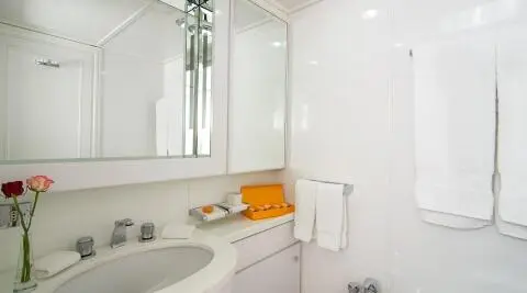 Interior view of a luxurious yacht bathroom with white fittings and orange towel