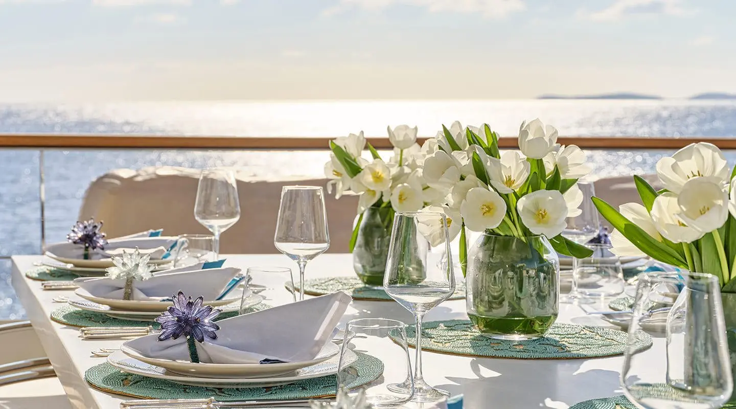 Dining table on La Pellegrina 1 yacht with white flowers and sea view at sunset