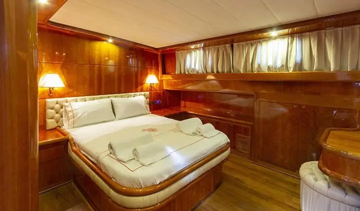 Cozy yacht cabin with large bed, wooden cabinets, and warm lighting